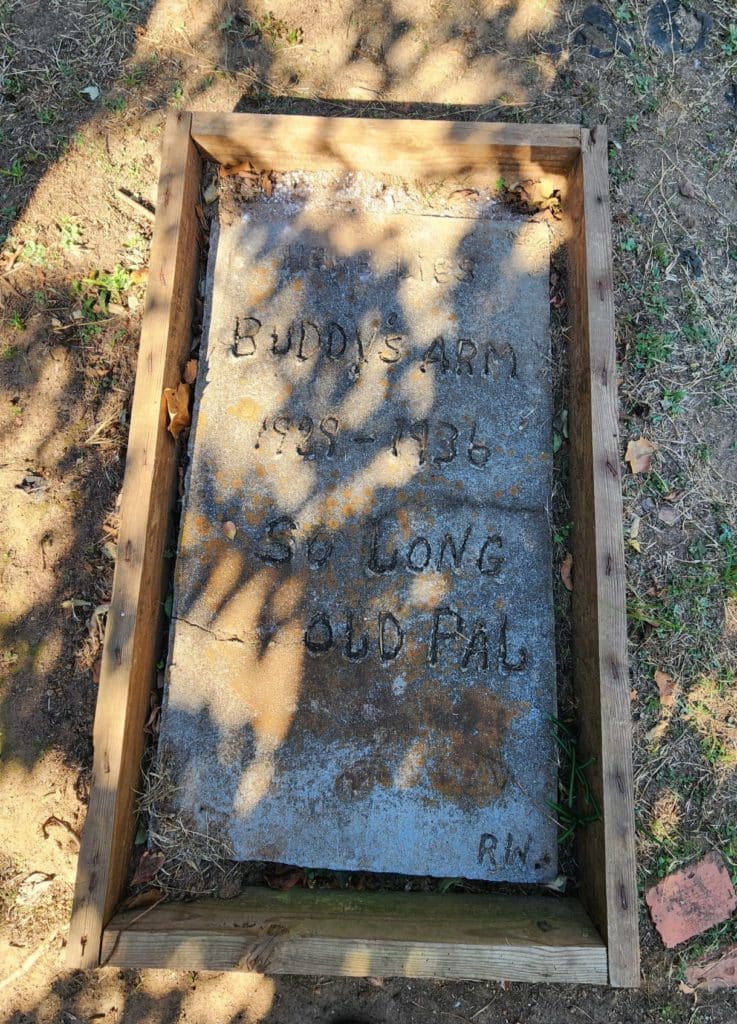grave stone with handwritten/carved words reading HERE LIES BUDDY'S ARM 1929-1936 SO LONG OLD PAL - Grave of Buddy's Arm in Historic Juliette, GA home to Fried Green Tomatoes