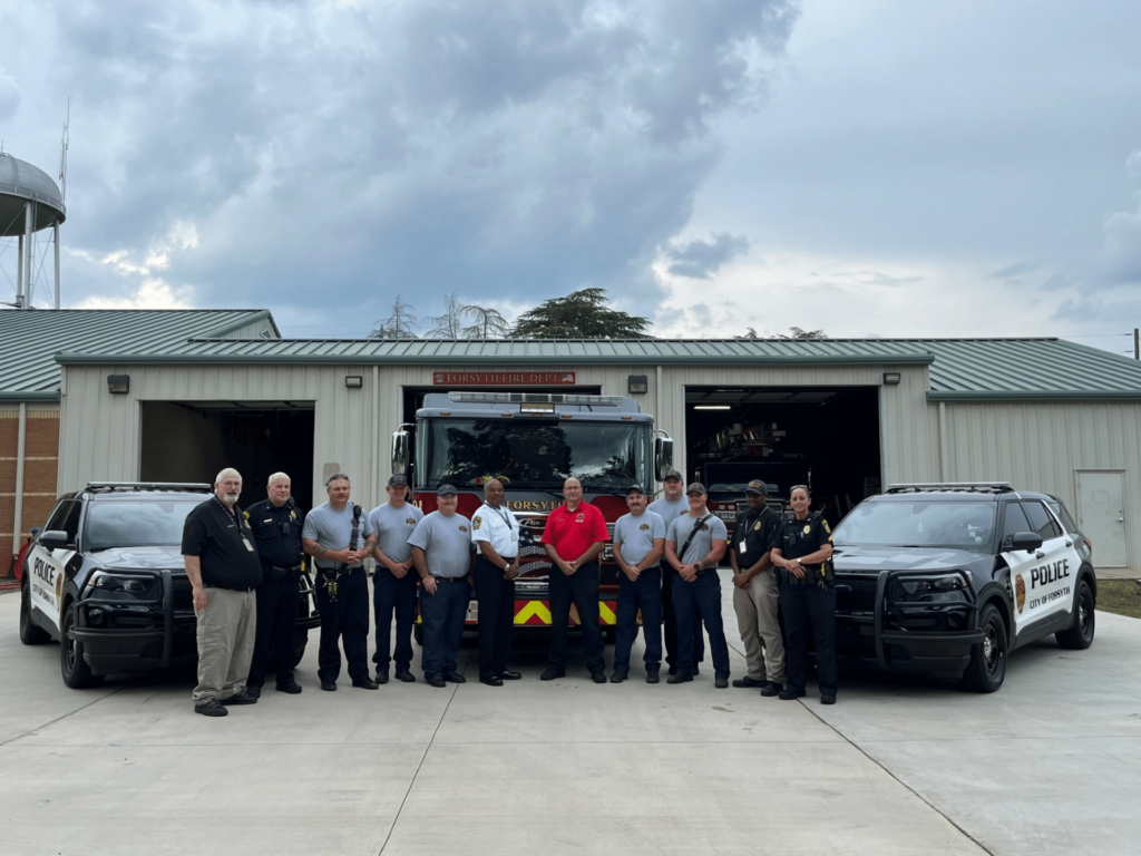 City of Forsyth Police and Fire Departments outside station in group photo with vehicles