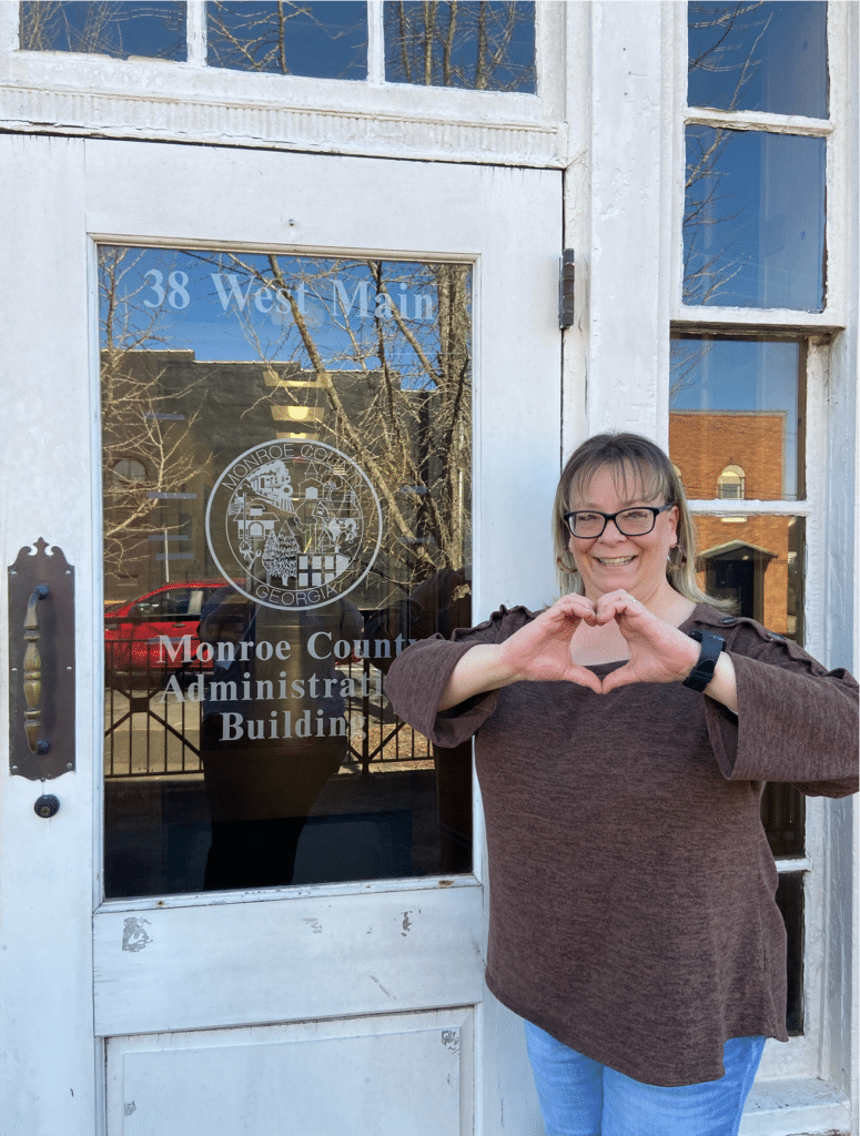 Monroe County Employee Ariyl Fuentes makes a heart with her hands outside the door of the Monroe County Office Building